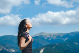 Long hair brunette girl on the top of the mountain enjoying fresh air